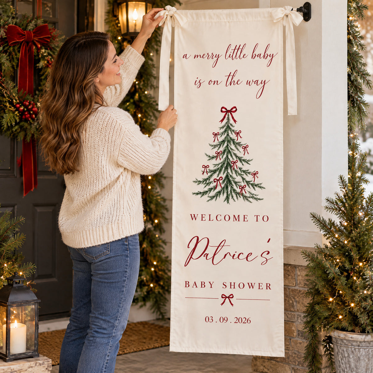 Personalized Christmas baby shower banner with a woman in a cream sweater tying it up on a decorated porch