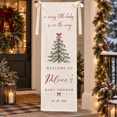 Personalized Christmas baby shower banner on a snowy porch with a wreath, candle lanterns and lit garland