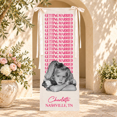 Personalized bachelorette party backdrop banner in pink in front of an arched doorway with vases of flowers