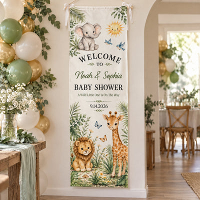 Personalized Safari Baby Shower Banner hanging on a wall with bows near balloons and a flower table