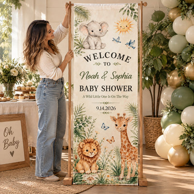 Personalized Safari Baby Shower Banner on a wooden stand with a woman holding it beside balloons and a sign