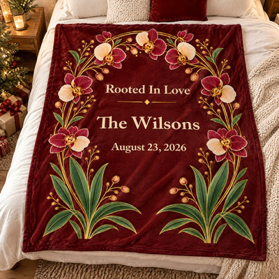 Personalized orchid arch blanket spread on a bed seen from above with a knit throw and wrapped gifts