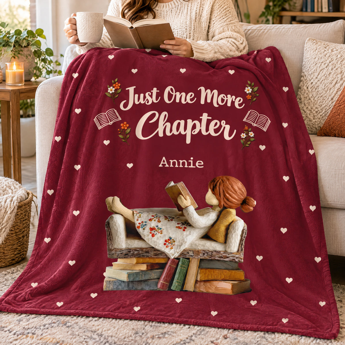 Personalized Blanket in deep red over a couch, a person holding a book and mug above the reading girl design