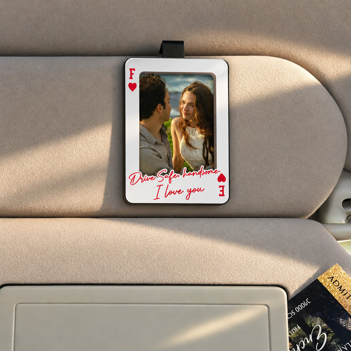 Personalized Car Visor Clip on a beige sun visor with a couple photo, red heart corners and handwritten message