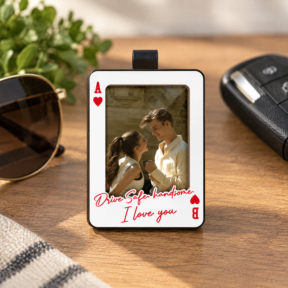 Personalized Car Visor Clip standing on a wooden table beside sunglasses, a car key fob and green leaves