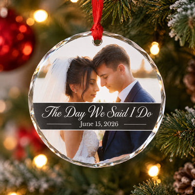Personalized glass ornament custom photo hanging on a Christmas tree with warm lights and a red bauble