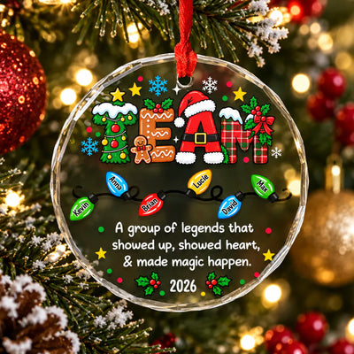 Personalized glass ornament custom team hanging on a tree branch with red baubles and a pinecone nearby
