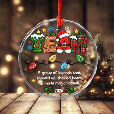 Personalized glass ornament custom team on a wooden table with a small lit tree and warm blurred lights