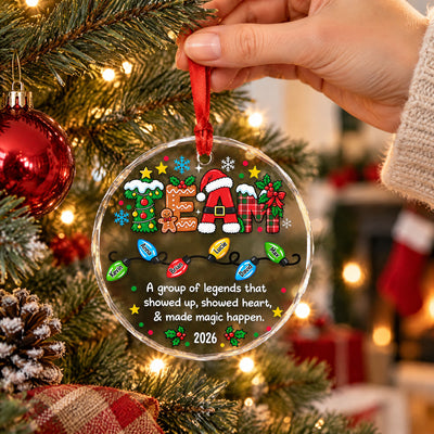 Personalized glass ornament custom team held up by hand near tree branches, a red stocking in the background