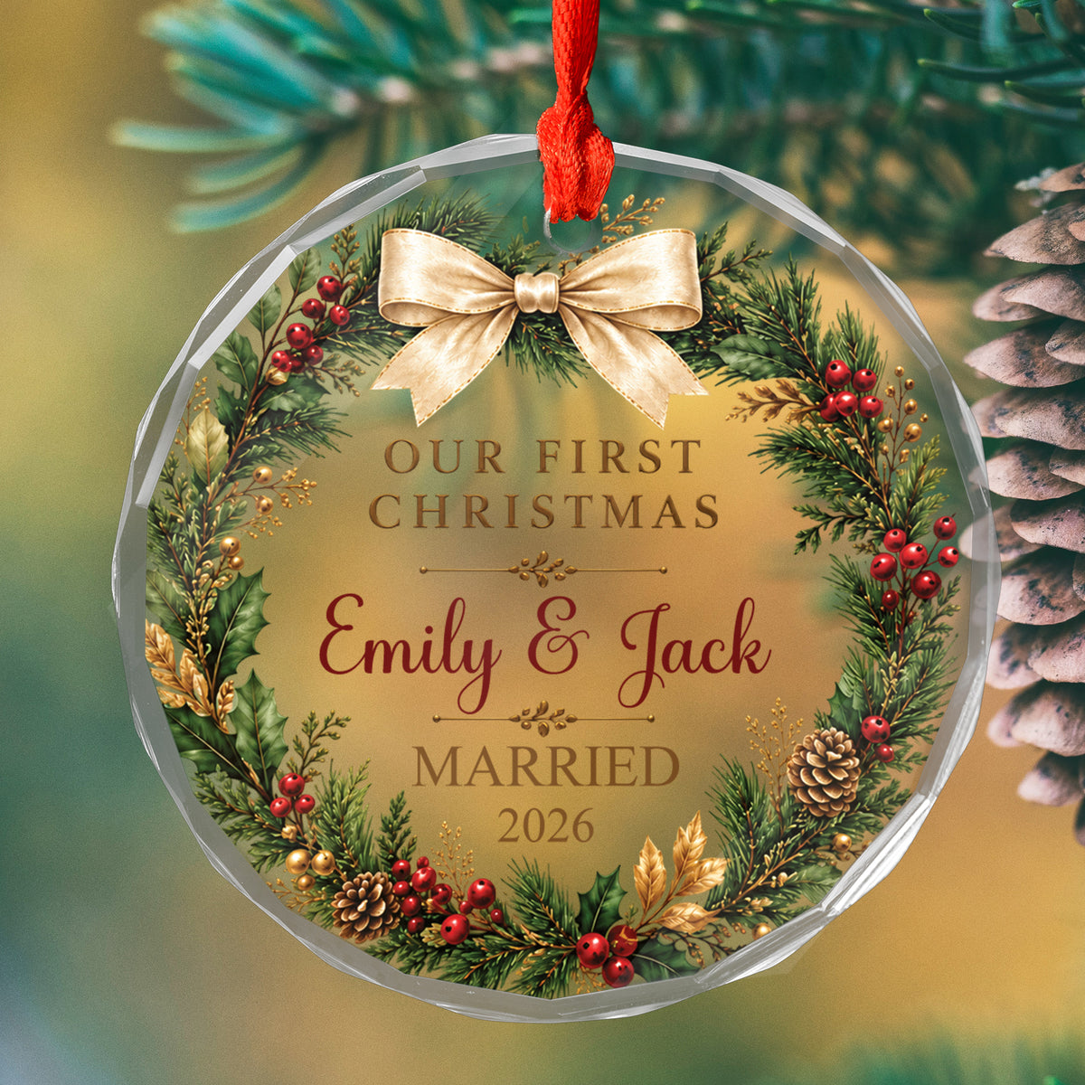 Personalized glass ornament first Christmas married close up against a blurred pine branch and pinecone
