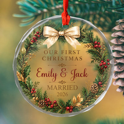 Personalized glass ornament first Christmas married hanging on a lit tree beside a red bauble, wreath and bow design