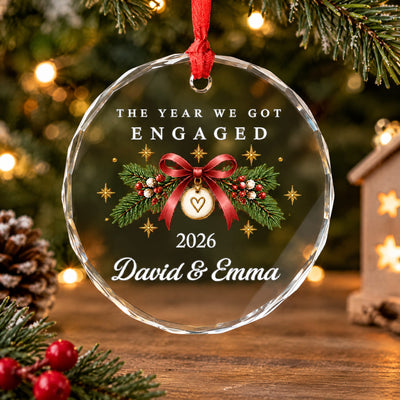 Personalized Glass Ornament Engaged Couple on a wooden table near pine branches, red berries and a pinecone