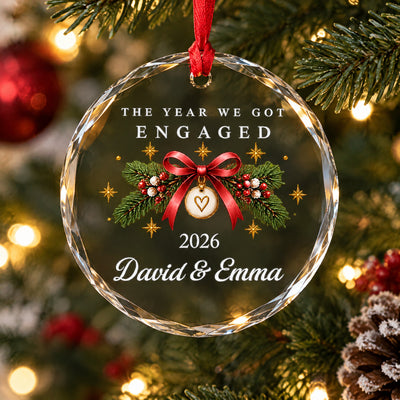 Personalized Glass Ornament Engaged Couple on a wooden table near pine branches, red berries and a pinecone