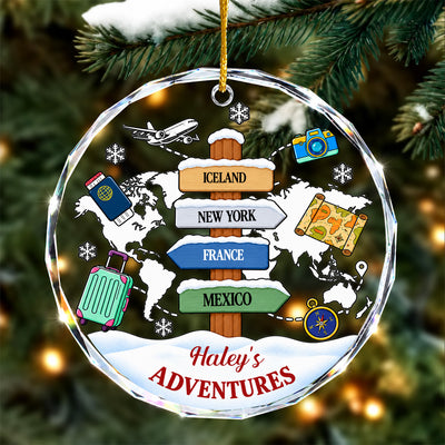 Personalized glass ornament adventure map hanging on a snowy pine branch, four destination signs on a world map