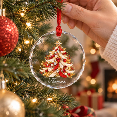 Personalized Christmas Tree Glass Ornament held by hand near a lit tree, red baubles and fireplace behind
