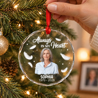 Personalized Glass Ornament Always In My Heart held by hand on a lit tree, woman's photo, feathers and dates