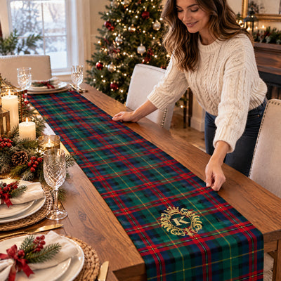 Personalized Christmas table runner being smoothed by a smiling woman beside a lit Christmas tree
