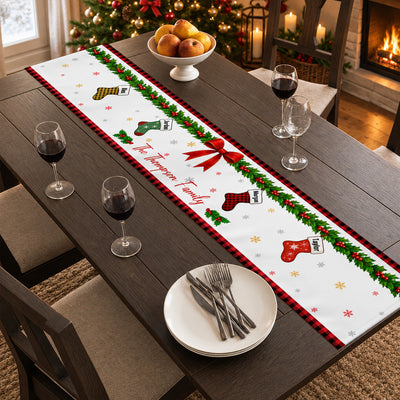 Personalized Christmas table runner on a dark wood table with wine glasses, a fruit bowl and stacked plates