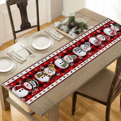 Personalized Snowman Family Christmas Table Runner on a wooden dining table with plates, napkins and candles