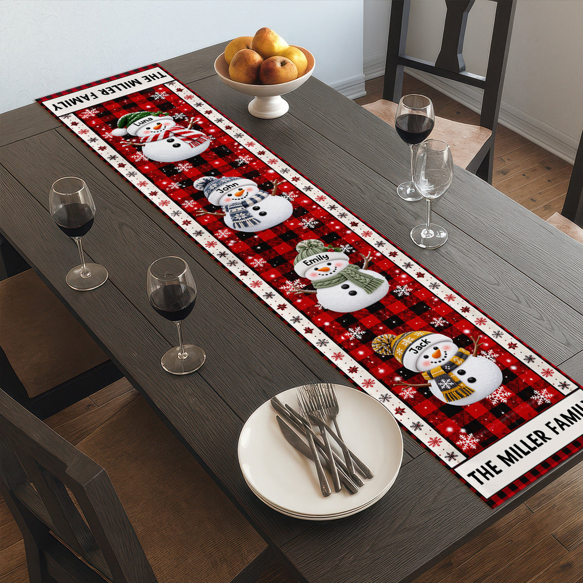 Personalized Snowman Family Christmas Table Runner on a dark table with wine glasses, a fruit bowl and stacked plates