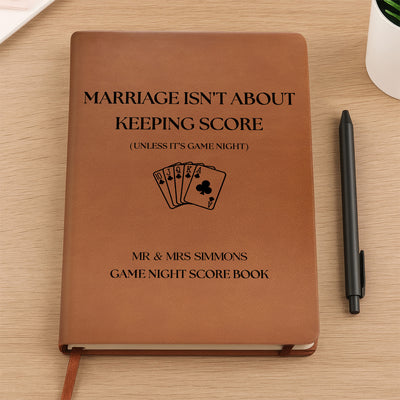 Personalized leather journal score book held upright in both hands against a cream sweater, playing cards design on cover
