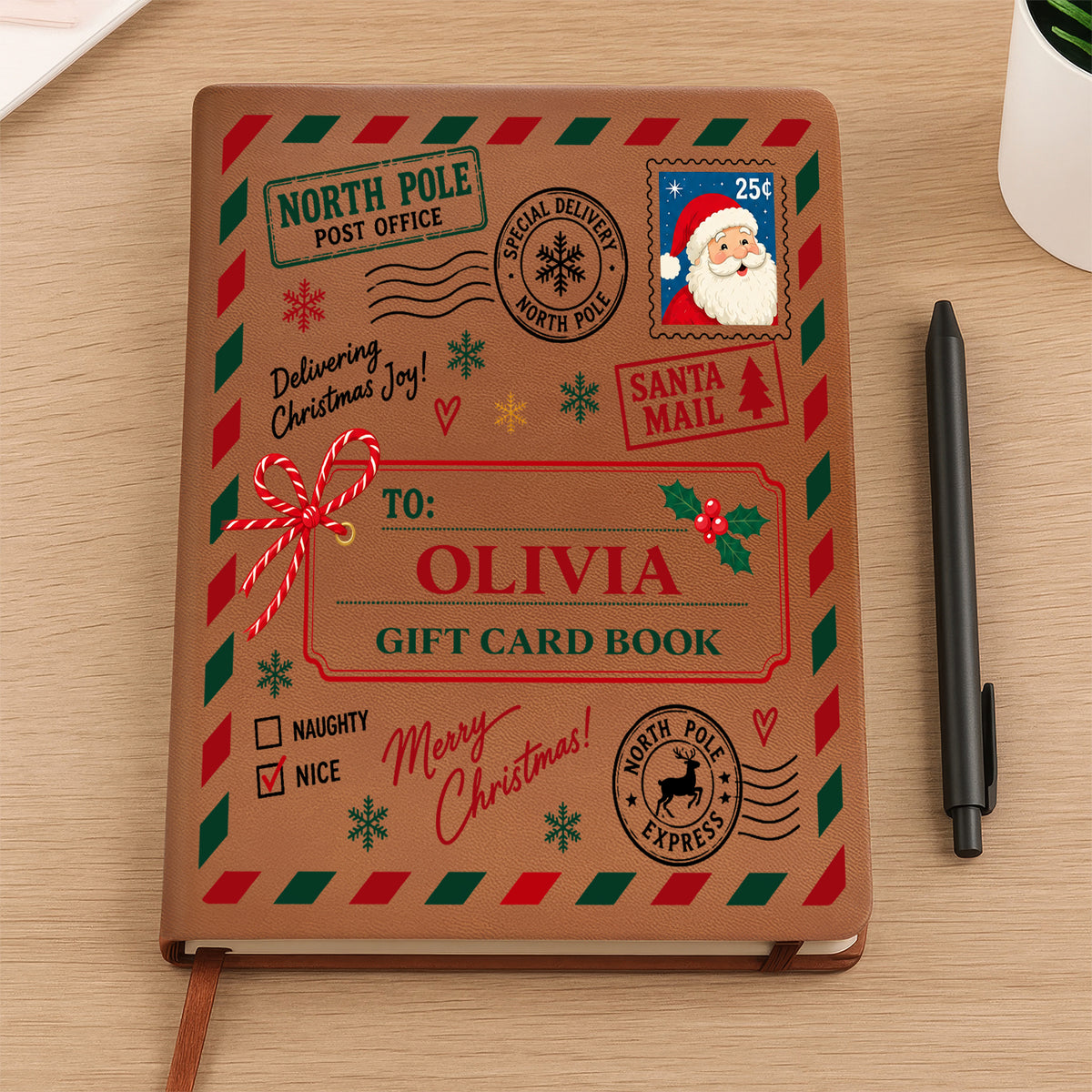 Personalized North Pole Santa Mail Leather Journal on a wooden desk beside a black pen, name Olivia on cover
