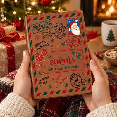 Personalized North Pole Santa Mail Leather Journal held in hands near a Christmas tree, gifts and a mug