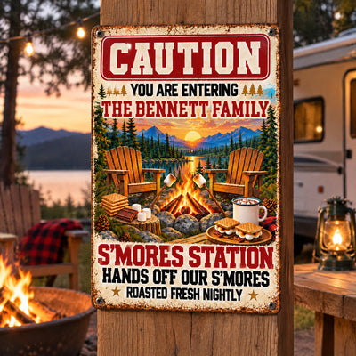 Personalized metal sign S’mores Station mounted on a wooden post with a camper and lake at sunset behind