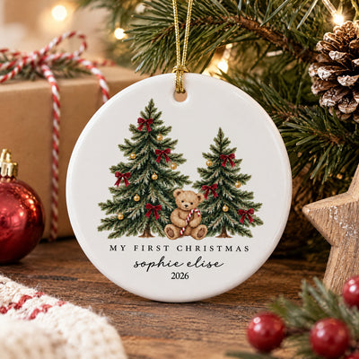 Personalized ceramic Christmas ornament teddy bear on a wooden table with a wrapped gift, pinecone and wooden star