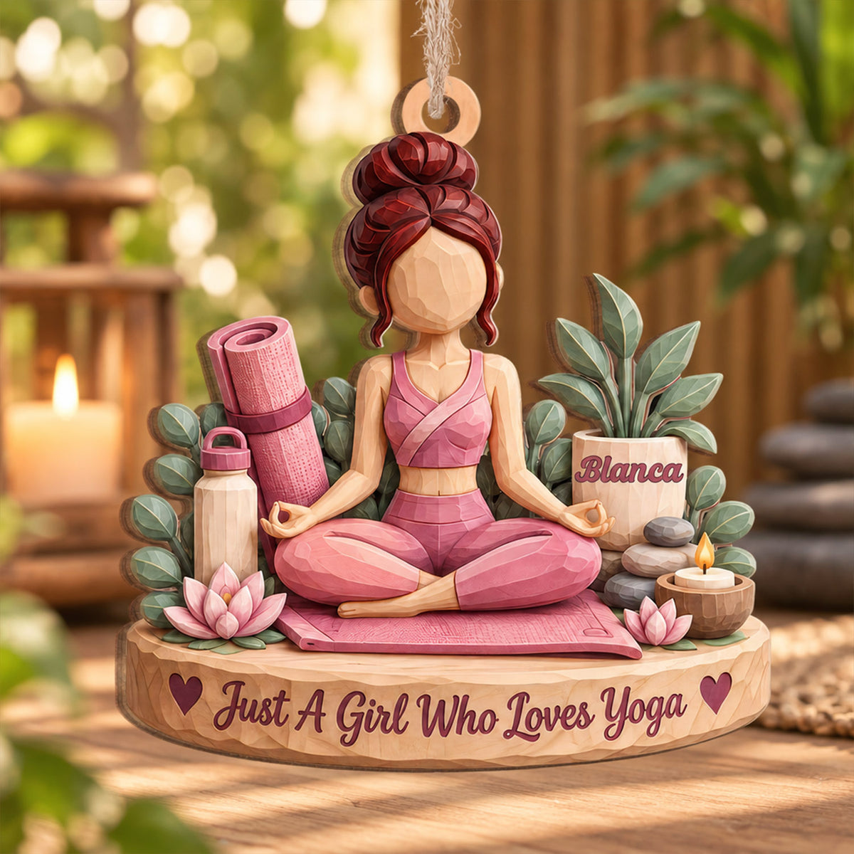 Personalized yoga wood ornament shown outdoors with a blurred garden, lit candle and stacked stones behind it