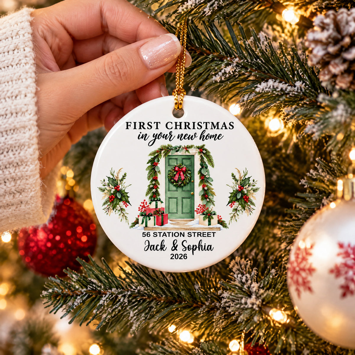Personalized Christmas Ornament Custom Couple Name held in hand by tree branches, red and white baubles nearby