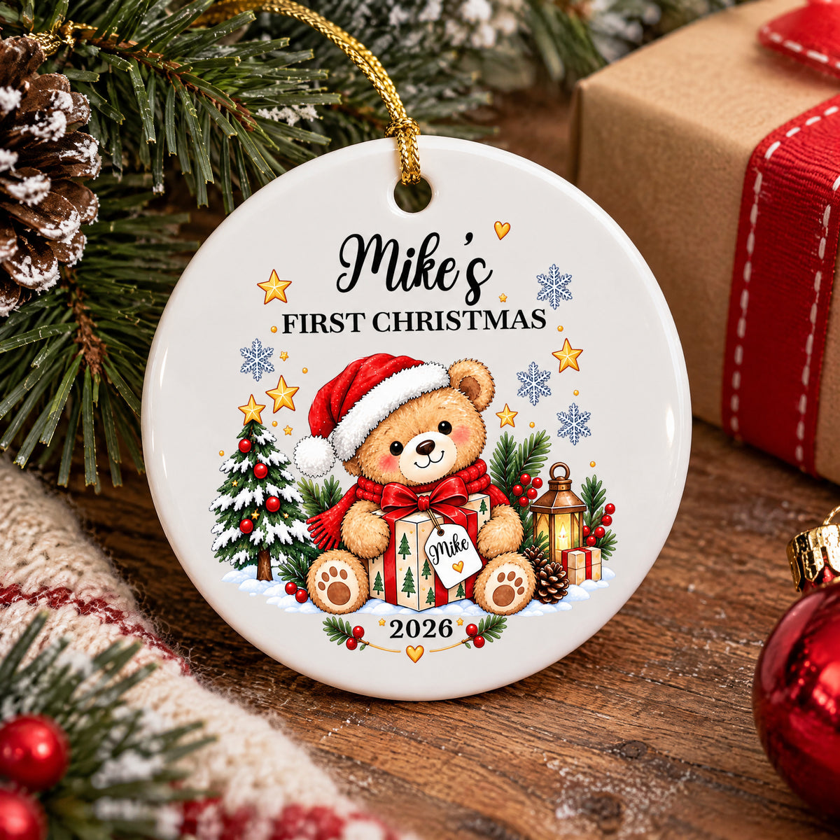 Personalized Ceramic Ornament First Christmas resting on a wooden surface beside a wrapped gift and pine branches
