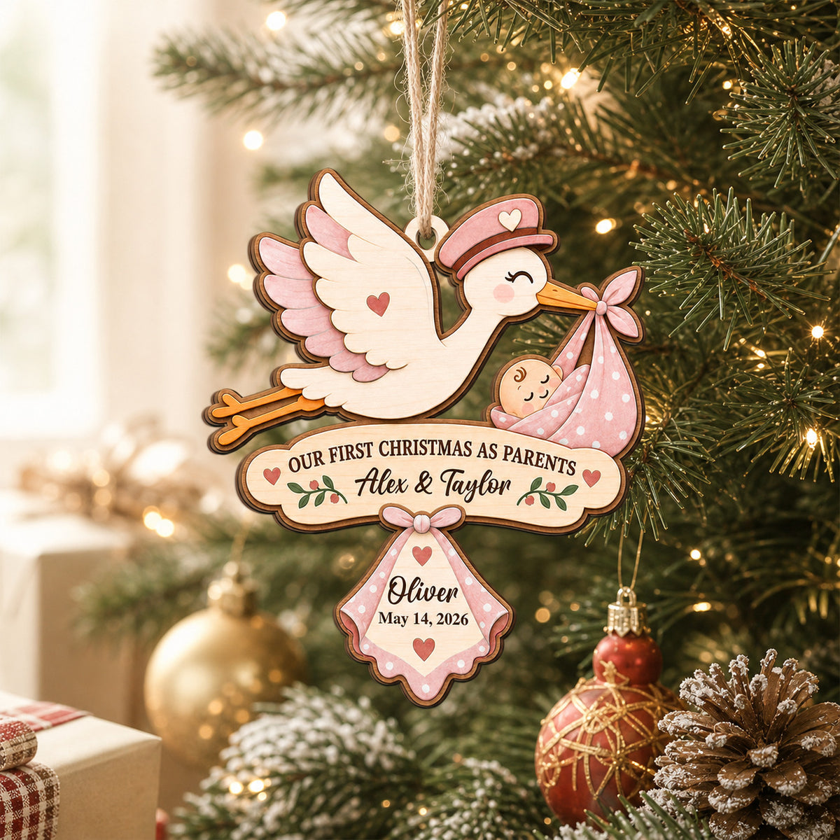 Our First Christmas As Parents Personalized Wooden Ornament, pink stork with baby hanging on a lit Christmas tree