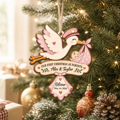 Our First Christmas As Parents Personalized Wooden Ornament, pink stork with baby hanging on a lit Christmas tree