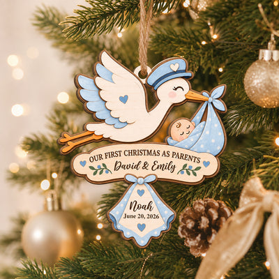 Our First Christmas As Parents Personalized Wooden Ornament, blue stork version on a tree beside gold baubles