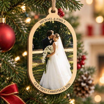 Personalized wooden photo ornament hanging on a Christmas tree beside a red glitter bauble and pinecone