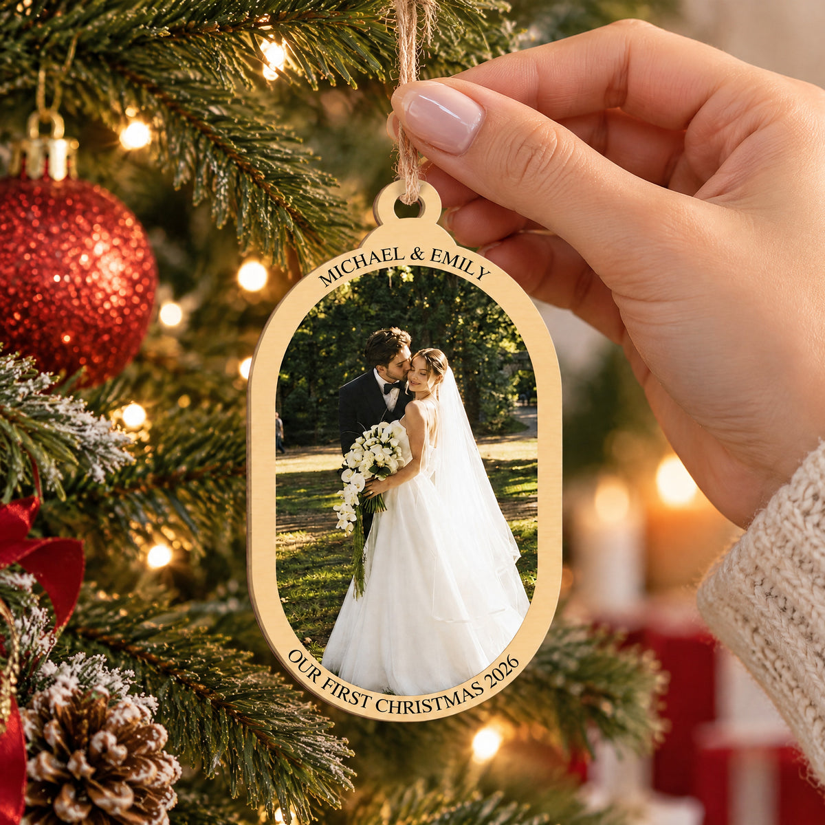 Personalized wooden photo ornament held by a hand by its twine loop in front of a lit Christmas tree