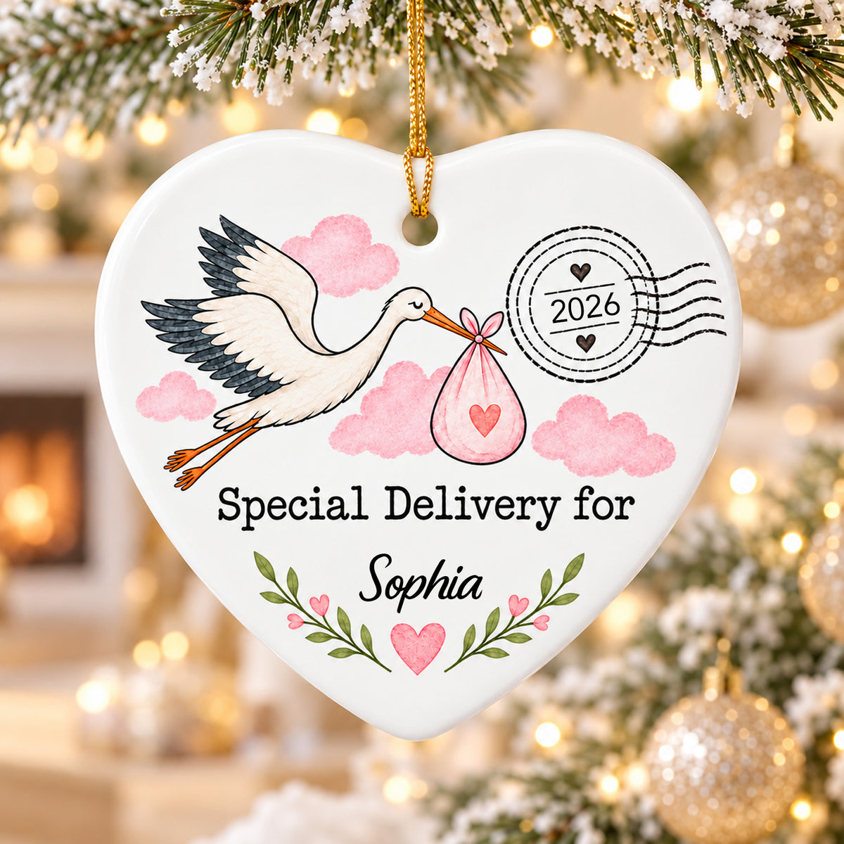 Personalized Stork Special Delivery Ceramic Ornament in pink with a name, hung near gold baubles and warm lights
