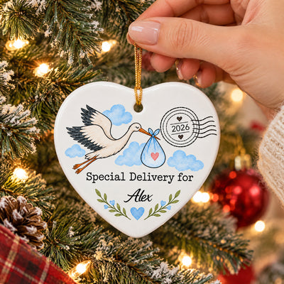 Personalized Stork Special Delivery Ceramic Ornament held by a hand on a tree beside a red bauble