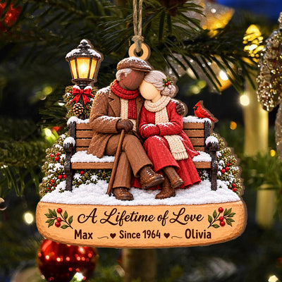 Personalized Wooden Couple Christmas Ornament hanging on a pine branch, couple on a snowy bench with names John and Lucie
