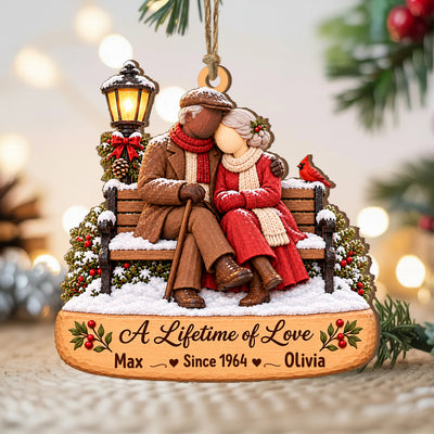 Personalized Wooden Couple Christmas Ornament on a soft knit surface with blurred lights and greenery behind it