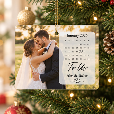 Rectangular ceramic ornament photo calendar hanging on a Christmas tree beside a red ball and pinecone
