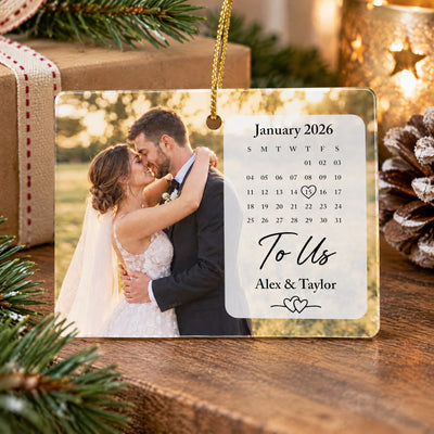 Rectangular ceramic ornament photo calendar standing on a wooden surface by a wrapped gift and pinecone