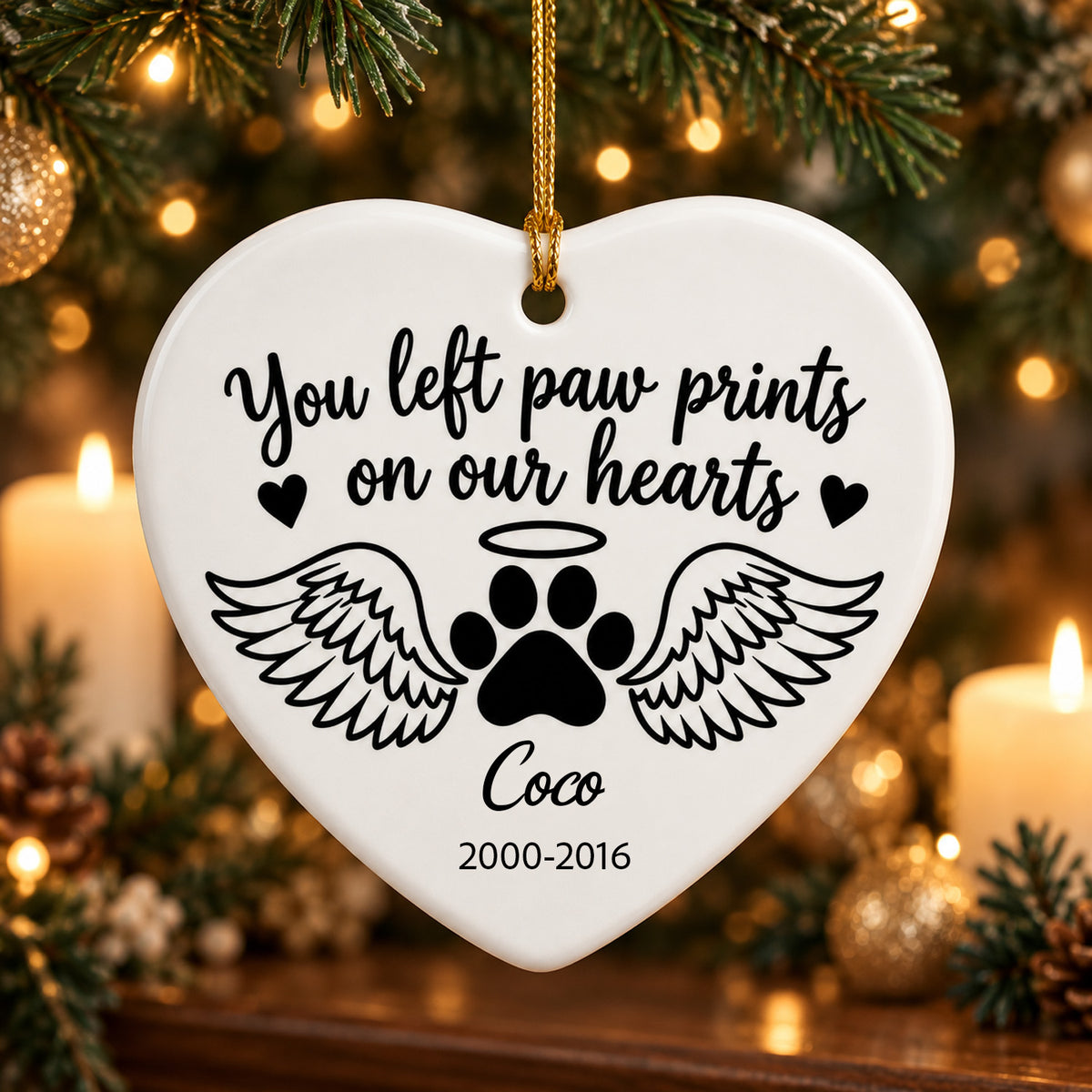 Personalized ceramic angel wings pet memorial ornament, heart shape with paw print and Coco, near candles and greenery