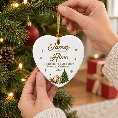 Personalized ceramic ornament first married Christmas held by hands in front of a tree and red gift box