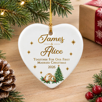 Personalized ceramic ornament first married Christmas on a light wood surface with a pinecone and red berries