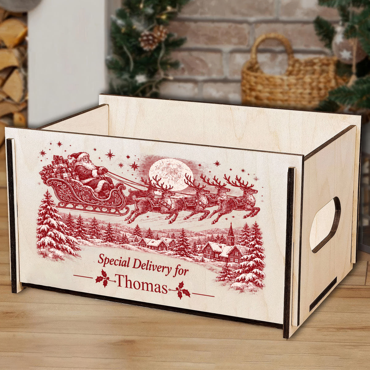 Personalized Christmas Eve Box on a wood floor with a fireplace, wicker basket and greenery in the background