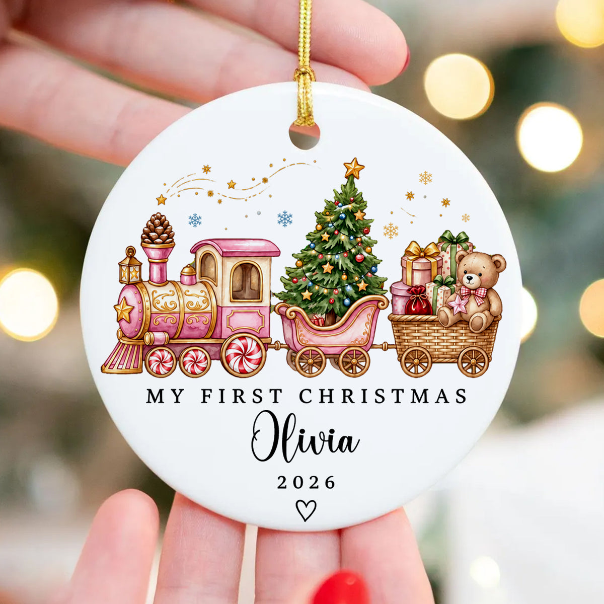 Personalized Custom First Christmas Ceramic Ornament with pink train held in a hand with blurred tree lights behind