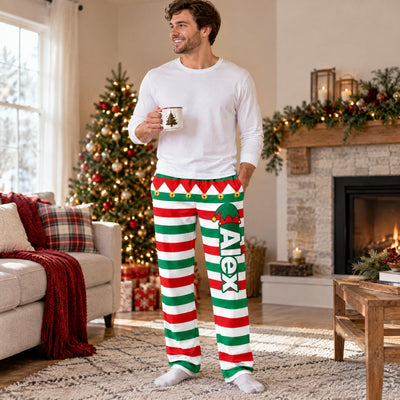 Personalized Elf Pajama Pants on a smiling man holding a mug in a living room with a lit tree
