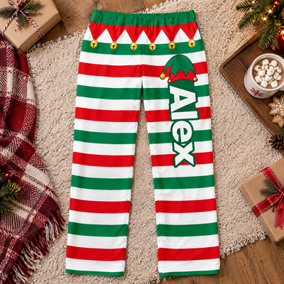 Personalized Elf Pajama Pants laid flat on a rug with a blanket, cocoa and gifts around